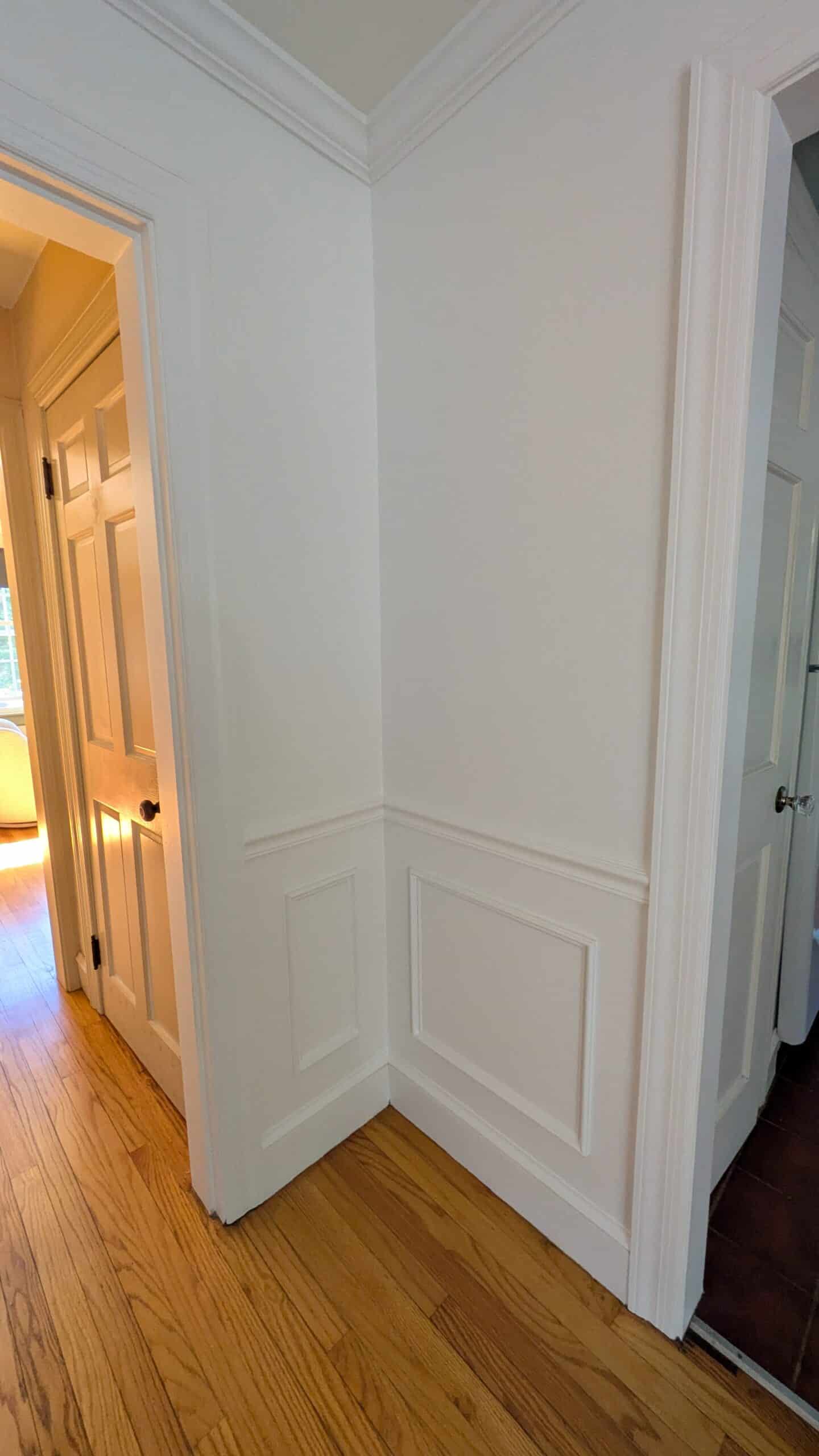 An image of a white wall with DIY wainscotting including chair rail and picture frame moulding.