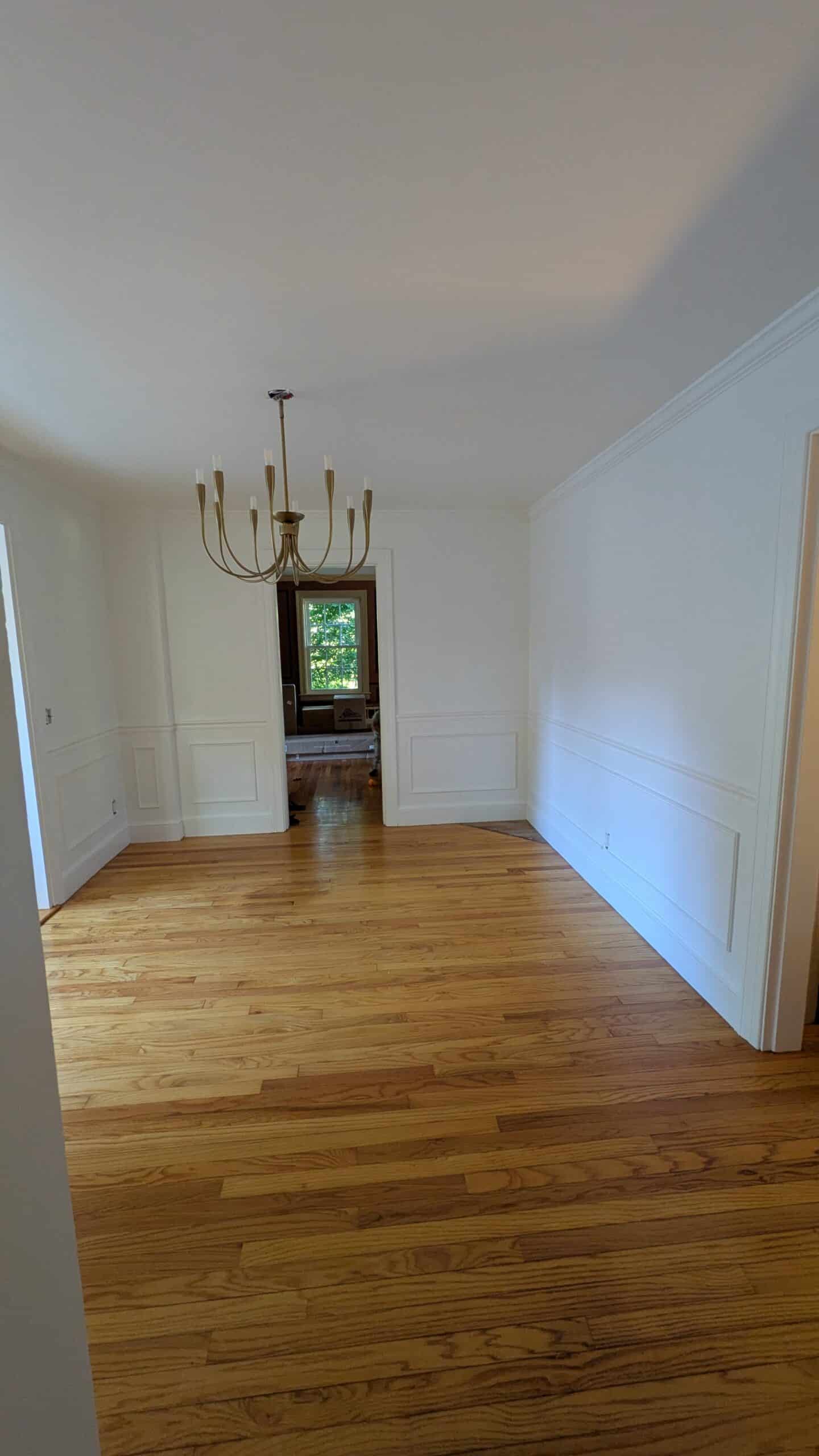 DIY wainscotting of a dining room and a beautiful modern chandelier.