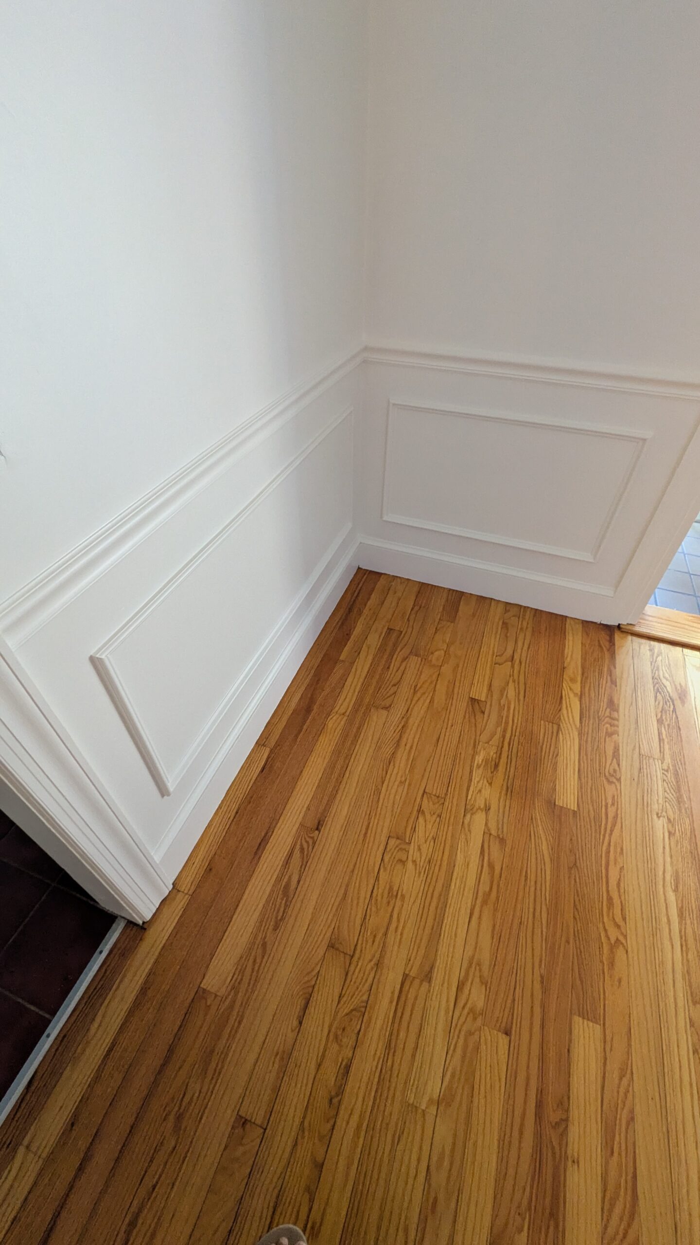 Beautiful white walls with DIY wainscotting showen with chair rail and picture frame moulding. Also hardwood floors.