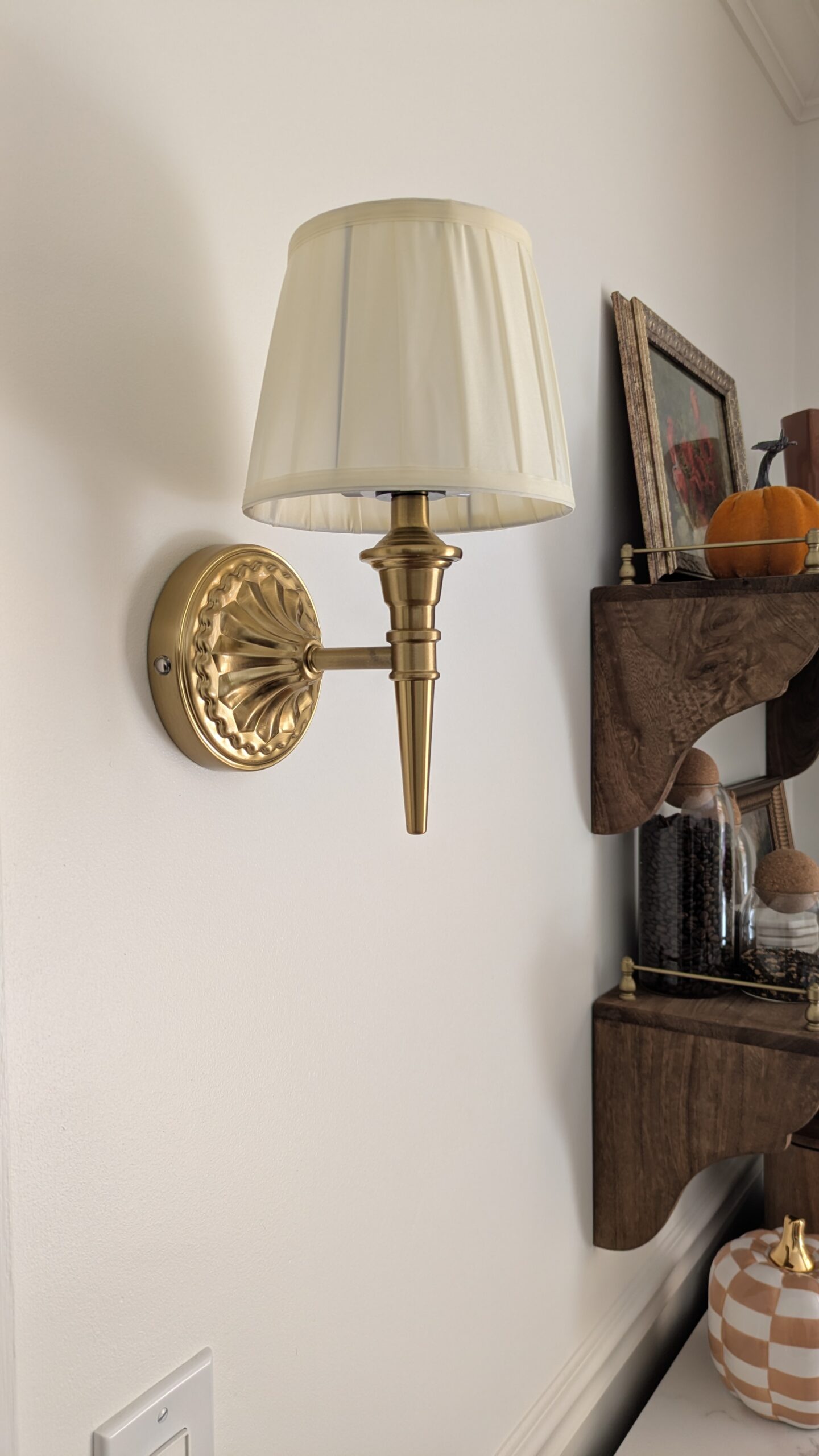 Wireless small sconce gold detail on a wall. With hints of a coffee bar shown in the background