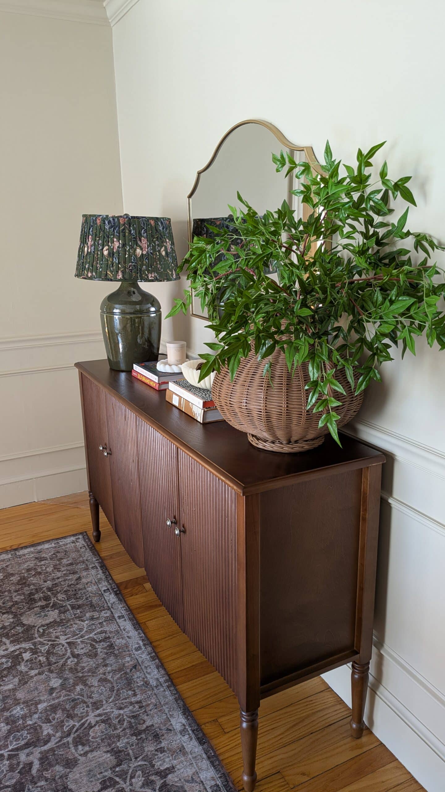 Hulala sideboard, oversized lamp and rattan vase. Books as decor and scalloped mirror. Brown rug. 