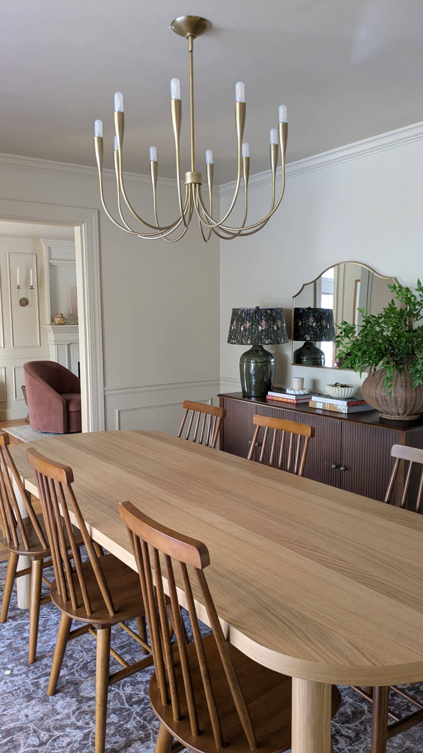 dining room, dining table, walnut chairs, dark walnut fluted sieboard, scalloped mirror, oversized lamps, oversized rattan vase and books 